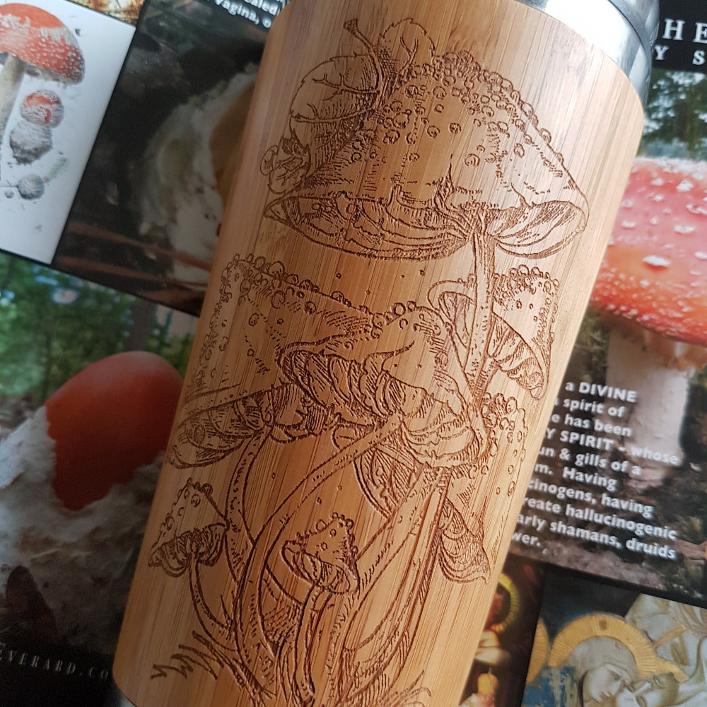 Bamboo Travel Mug with Amanita mushrooms engraving in close up on colorful mushroom book page background